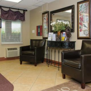 A cozy waiting room with leather chairs, wall art, and a mirror.