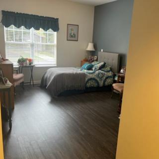 A cozy bedroom with a large window, featuring a neatly made bed and tasteful decor.