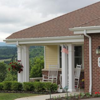 A quaint porch with rocking chairs offers a serene view of the surrounding landscape.