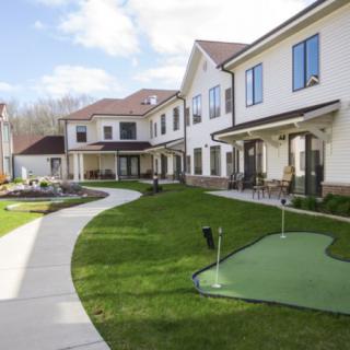 A large residential building with a well-maintained lawn and concrete sidewalks under a sunny sky.