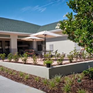 A welcoming outdoor patio area with shade umbrellas, surrounded by lush landscaping.