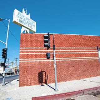 A sunlit view of a brick building with a prominent sign and traffic light against a clear blue sky.