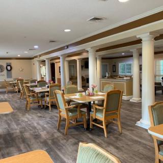 An elegantly designed dining area with wooden tables and cushioned chairs, featuring decorative pillars and a cozy ambiance.