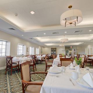 An elegant dining room with neatly arranged tables and chairs, featuring chandeliers and a sophisticated ambiance.