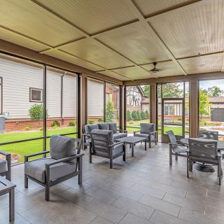 A modern screened porch with comfortable outdoor seating overlooking a garden.