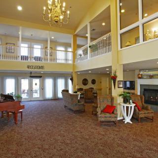 A spacious living room with a chandelier, fireplace, and piano.