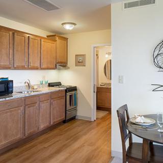 A modern kitchen with wooden cabinets, a dining area, and household appliances.