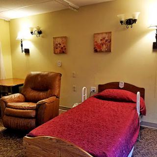 A cozy room featuring a single bed, a comfortable armchair, and decorative wall art.