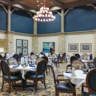 Elegant dining room with beautifully set tables and a large chandelier.