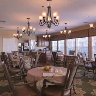 A spacious dining room with several tables and elegant chandeliers.