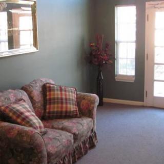 A cozy living room with a patterned sofa and decorative pillows, featuring a large window and a mirror on the wall.