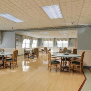 An empty dining area with several tables and chairs, well-lit with ceiling lights.
