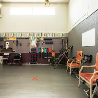 A spacious fitness studio featuring exercise equipment and seating, designed for workouts and training sessions.