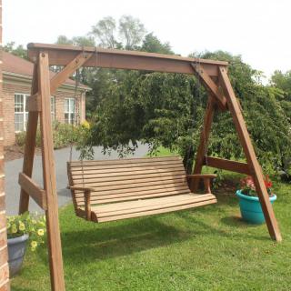 A wooden swing set in a garden area, surrounded by grass and potted plants.