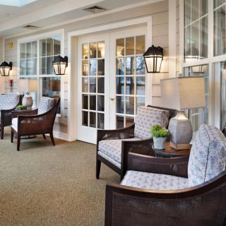 A cozy sunroom with comfortable armchairs, elegant lamps, and large windows.