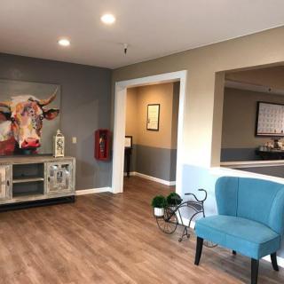 A modern waiting area featuring a blue chair, decorative art, and wood flooring.
