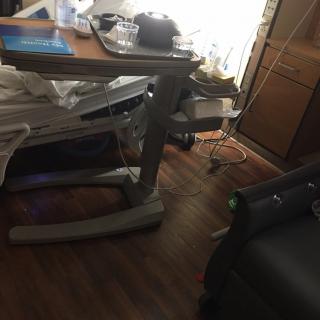A hospital room with a bed, medical equipment, and furniture.