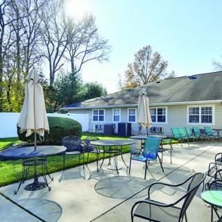 A sunny patio with outdoor seating, tables, and umbrellas.