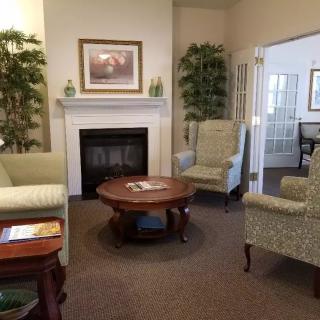 A cozy living room with a fireplace, comfortable seating, and decorative plants.