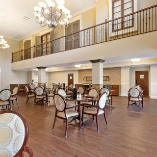 A spacious and elegant dining area with chandeliers and wooden flooring.