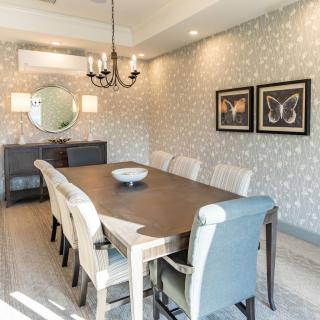 A stylish dining room with a long table, upholstered chairs, and elegant decor.