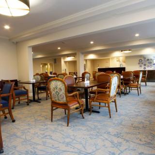 A spacious dining room with elegant chairs and tables arranged neatly on a carpeted floor.
