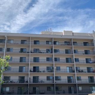 A multi-story apartment building with balconies under a partly cloudy sky.