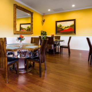 A cozy dining area with wooden flooring, yellow walls, and elegant furniture.