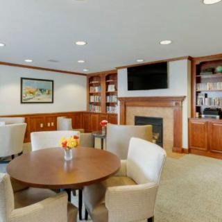 A cozy living room with a fireplace, television, bookshelves, and comfortable seating around a table.