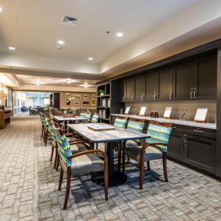 A modern library space with a long table and chairs, surrounded by shelves and cabinets.