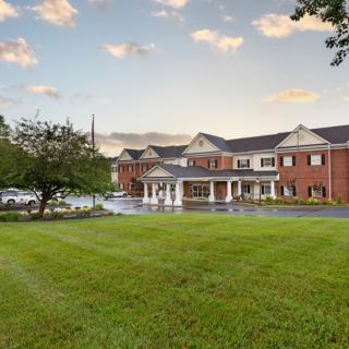 A large brick building with a well-maintained grass lawn under a partly cloudy sky.