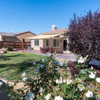 A well-maintained backyard with a lawn, flowers, and trees adjacent to a house.