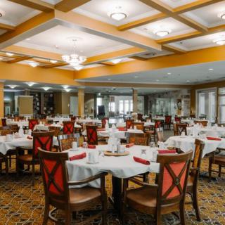 An elegantly set dining room with multiple tables and chairs arranged neatly.