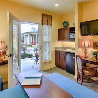 A cozy living area with a kitchenette, featuring warm yellow walls and ample natural light.