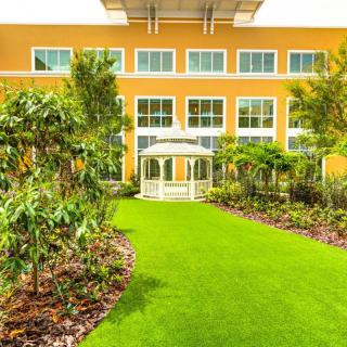 A vibrant garden with a lush green lawn in front of a yellow building.