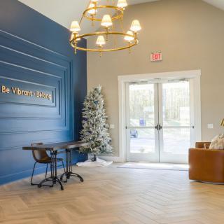 A modern lobby with stylish decor including a Christmas tree, chandelier, and seating area.