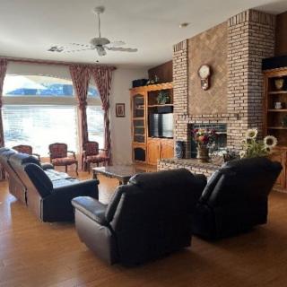 A cozy living room with a brick fireplace, leather sofas, and large windows.