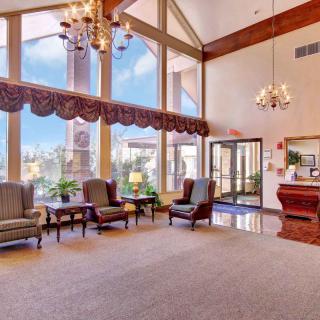 A spacious hotel lobby with large windows, elegant chandeliers, and comfortable seating.