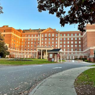 A view of a large hotel building surrounded by trees and a clear sky.