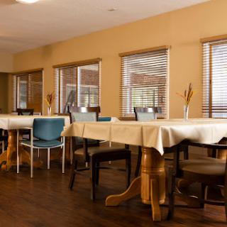 A spacious dining area with neatly arranged tables and chairs, featuring warm neutral tones and natural light.