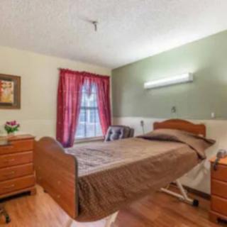 A cozy bedroom features a hospital-style bed, wooden furniture, and vibrant red curtains.