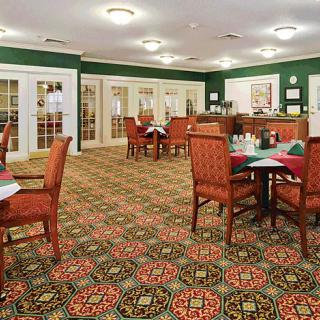 A cozy dining area with patterned carpet and neatly arranged tables and chairs.