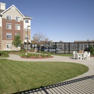 An outdoor view of a residential building with a garden and seating area.