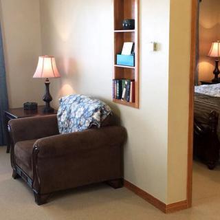 A cozy corner of a living room with an armchair next to a lamp and built-in shelving.