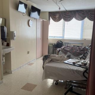 A hospital room with a bed, medical equipment, and a television.
