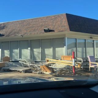 An abandoned building surrounded by scattered debris and furniture.