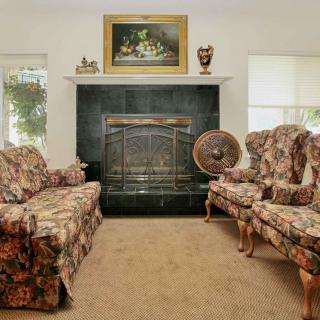 A traditionally decorated living room with floral patterned sofas and a central fireplace.