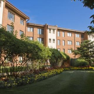 A picturesque view of a brick building with a lush garden and clear blue sky.