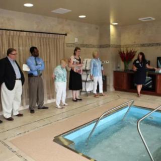 A group of people in formal attire stand around an indoor pool.