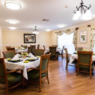 A well-decorated dining area with neatly arranged tables and chairs, featuring elegant lighting and a cozy atmosphere.